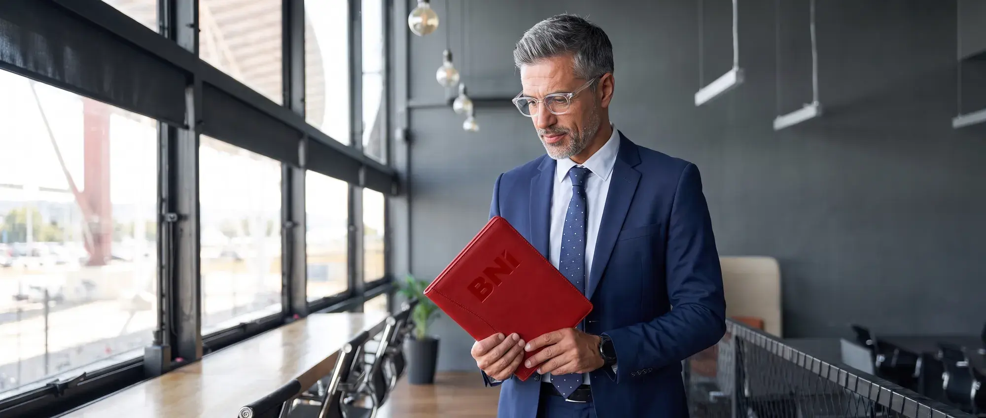 Przedsiębiorca z czerwoną teczką BNI w przeszklonym biurze